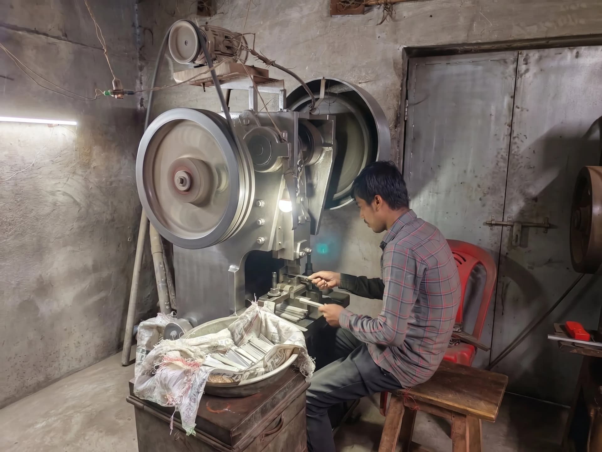 Operator forming hardware parts on a power press at the Nexus Fittings factory in Aligarh